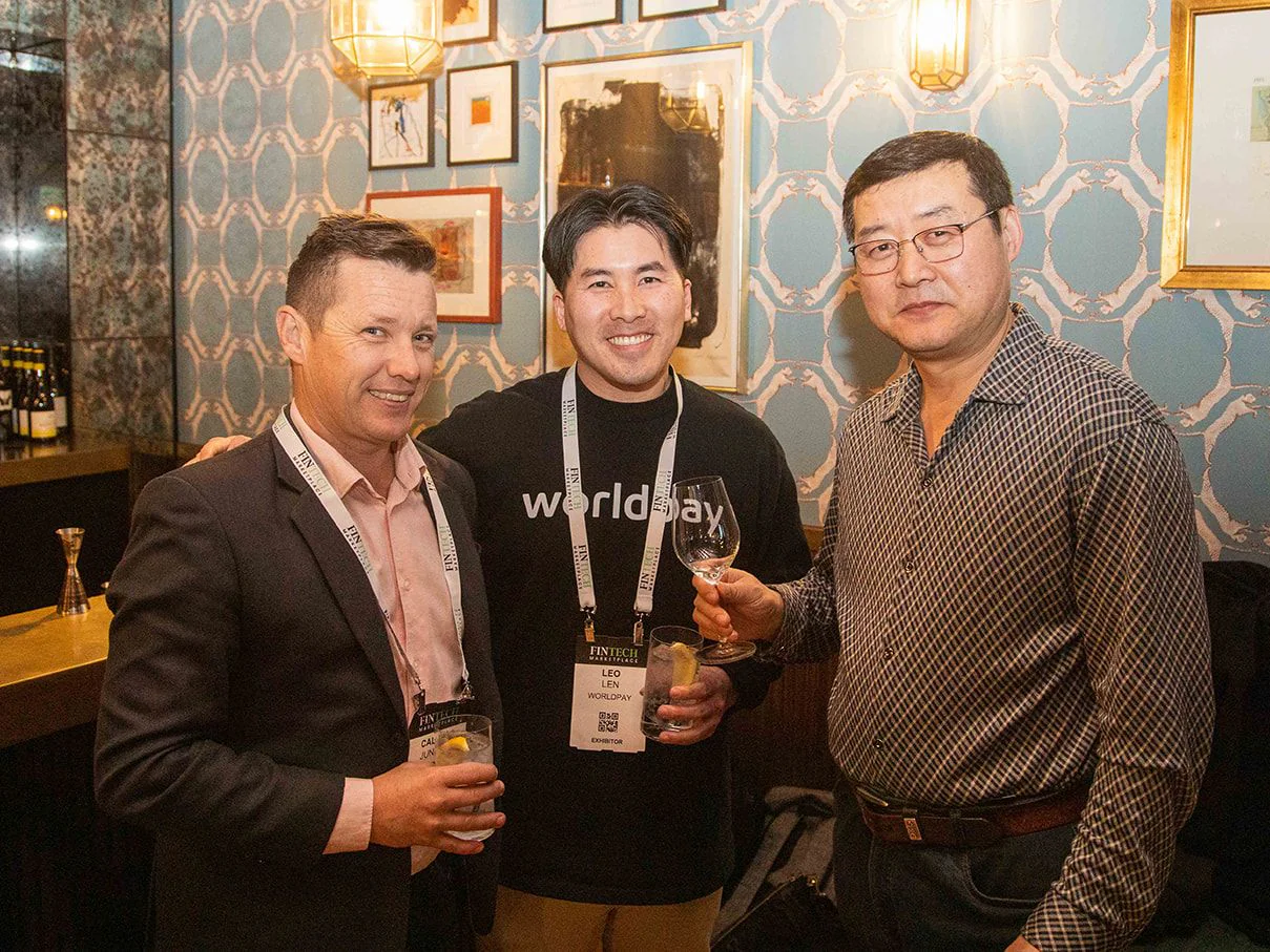Three guests with drinks posing beside the bar