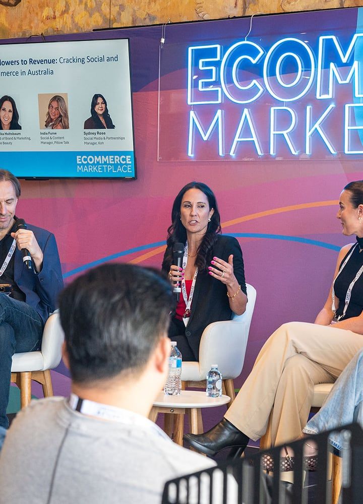 A panellist speaking into a microphone on the Ecommerce Marketplace stage, with the session screen behind her