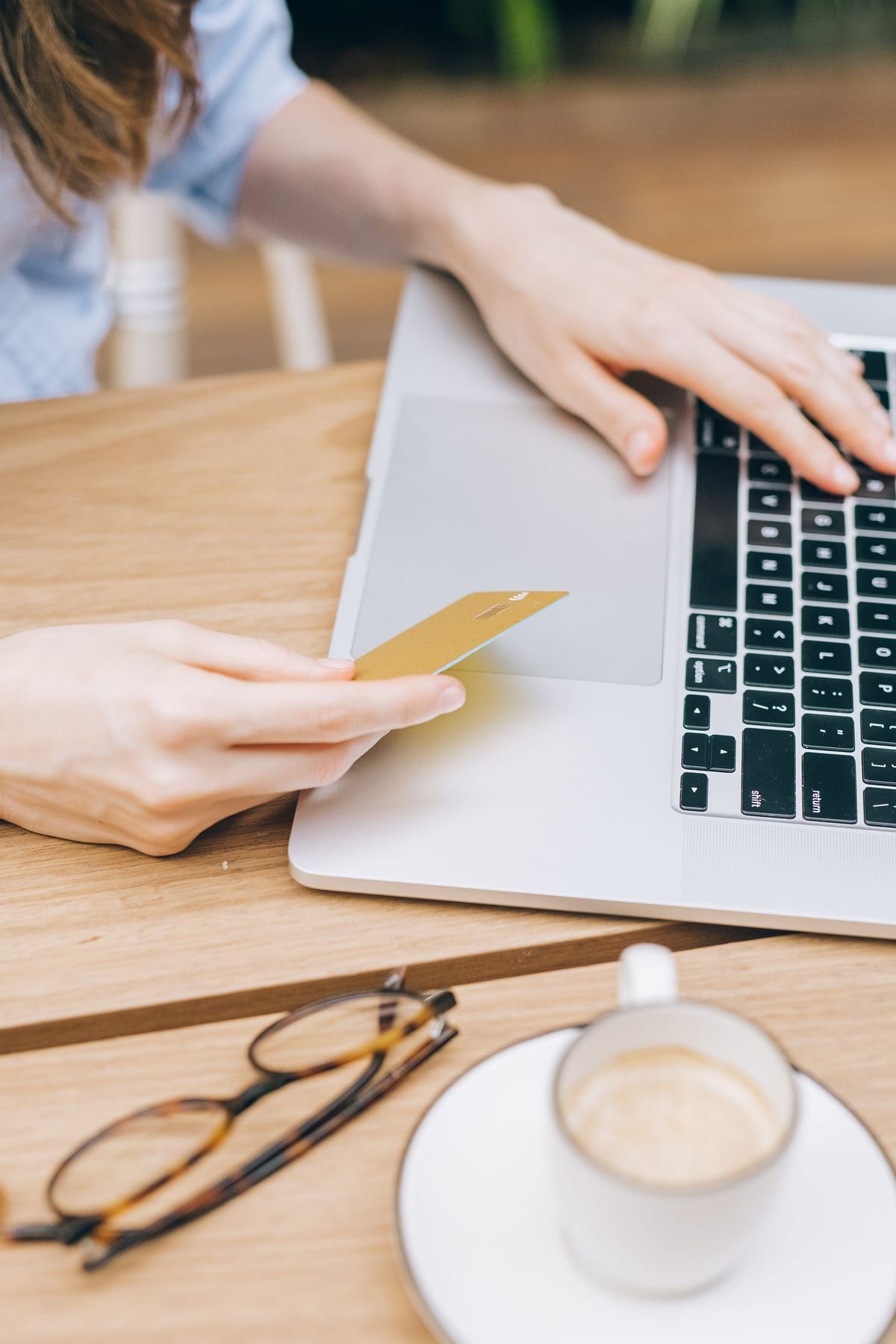A shopper paying for an online order on a laptop, card in hand