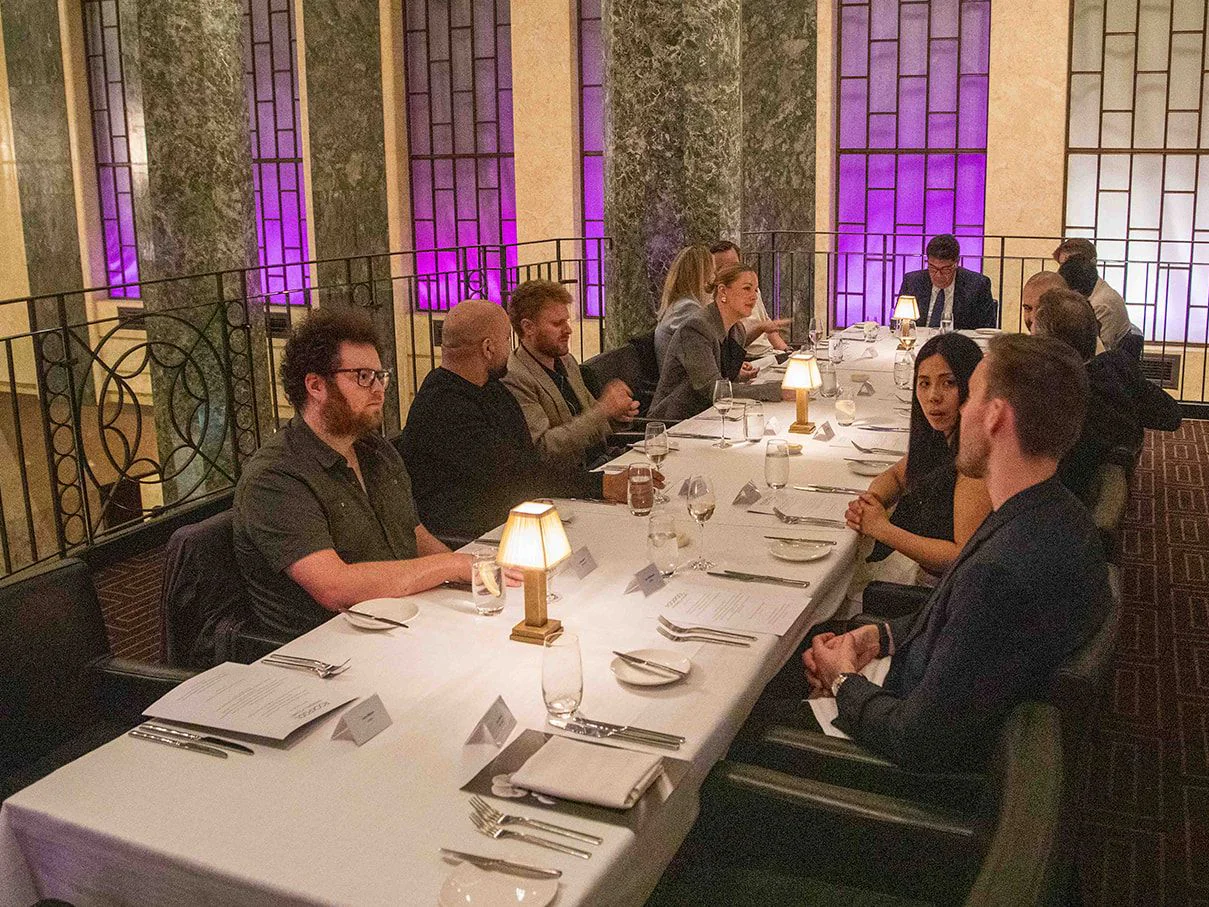 Retail executives at a long candlelit table in a marble-columned dining room