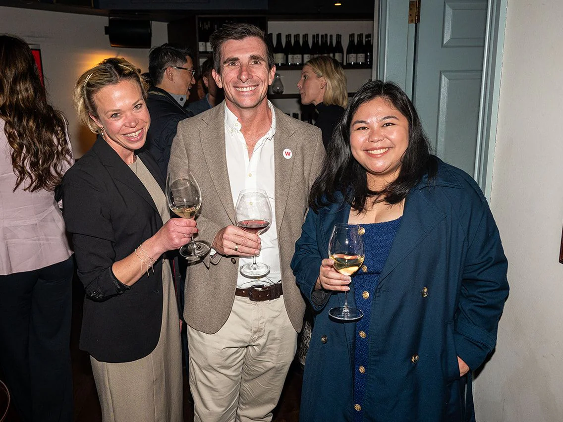 Three dinner guests smiling with glasses of wine at The Gidley