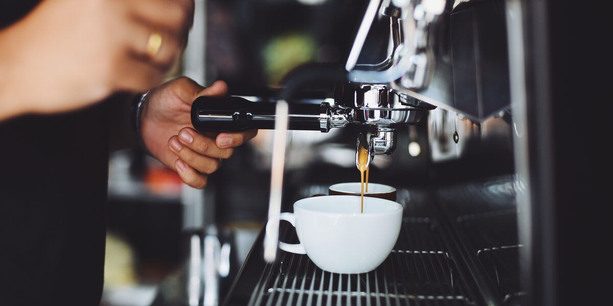 A barista pulling espresso shots into cups on a coffee cart counter