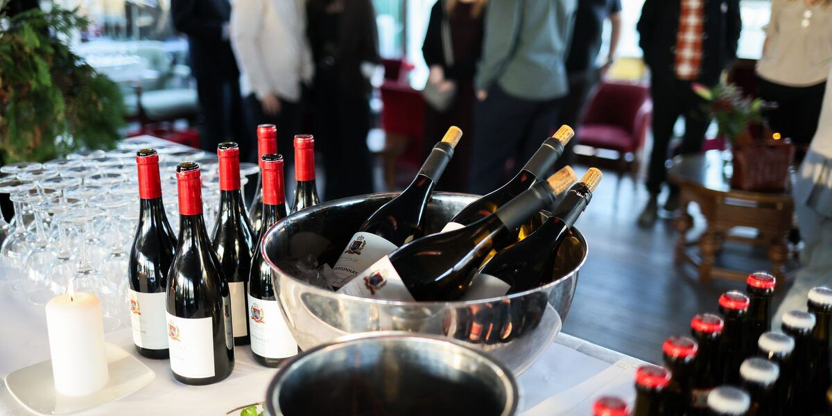 Wine and drinks laid out for an evening reception, guests mingling behind