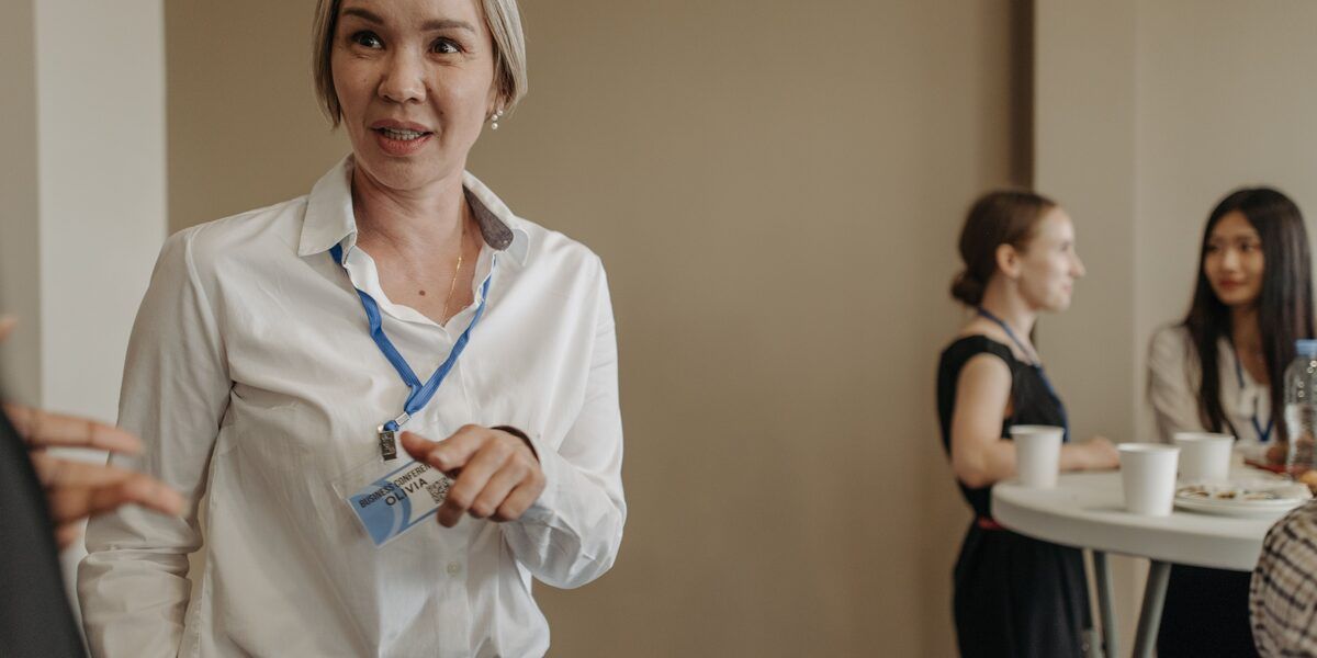 A delegate wearing a conference lanyard chatting at a networking function