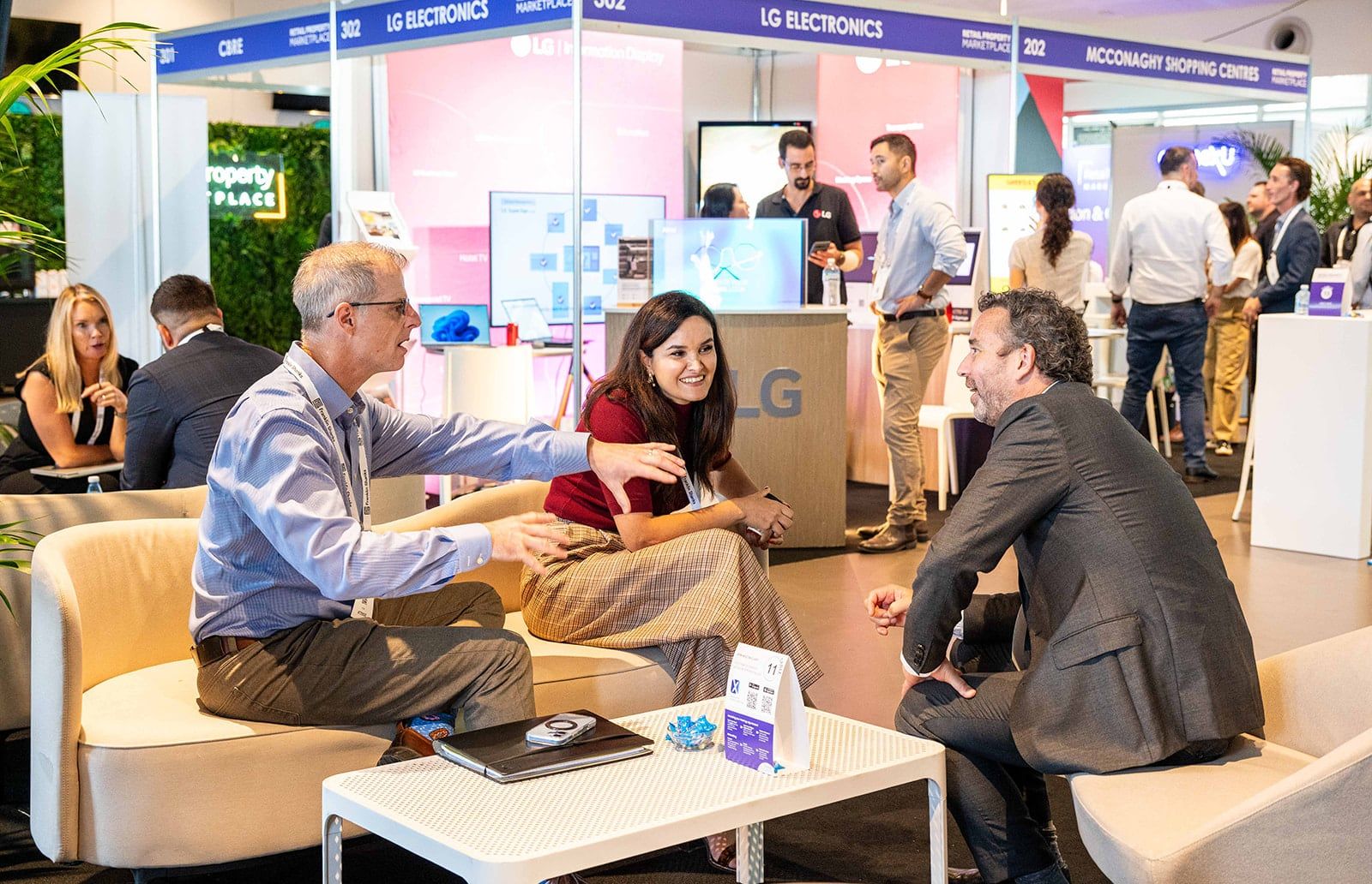 Three delegates meeting on lounge sofas beside the exhibitor stands