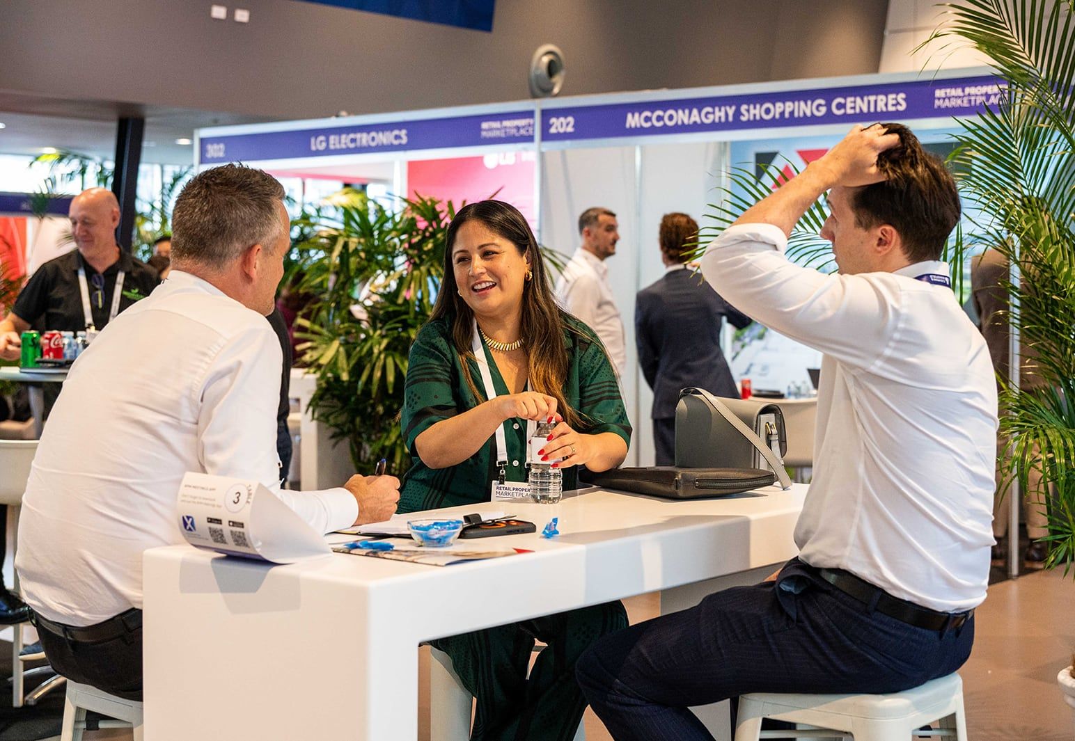 A meeting at a table in front of the shopping centre and electronics stands