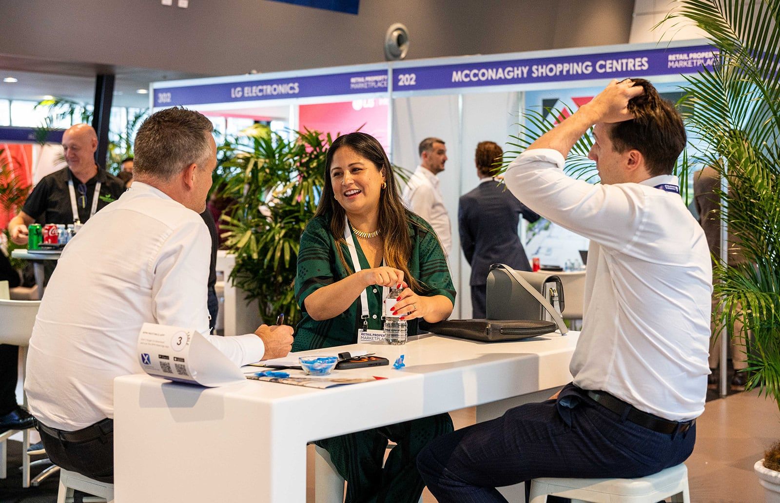 A meeting at a table in front of the shopping centre and electronics stands
