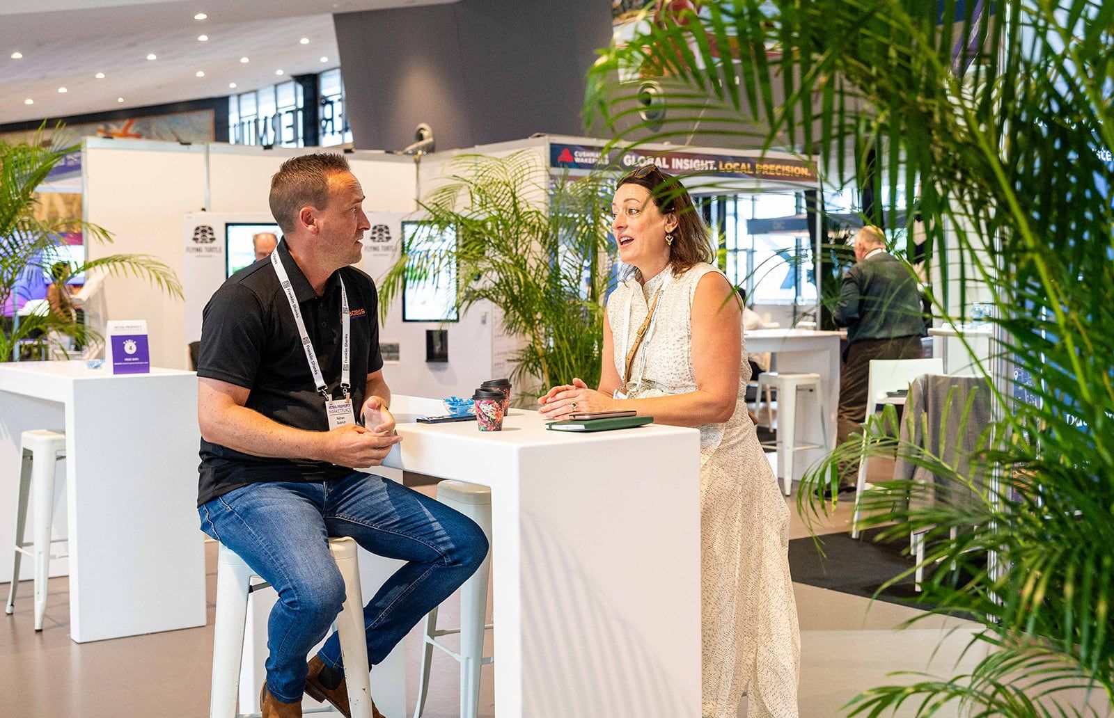 Visitors gathered around a brightly branded exhibitor stand with a large retro-style display