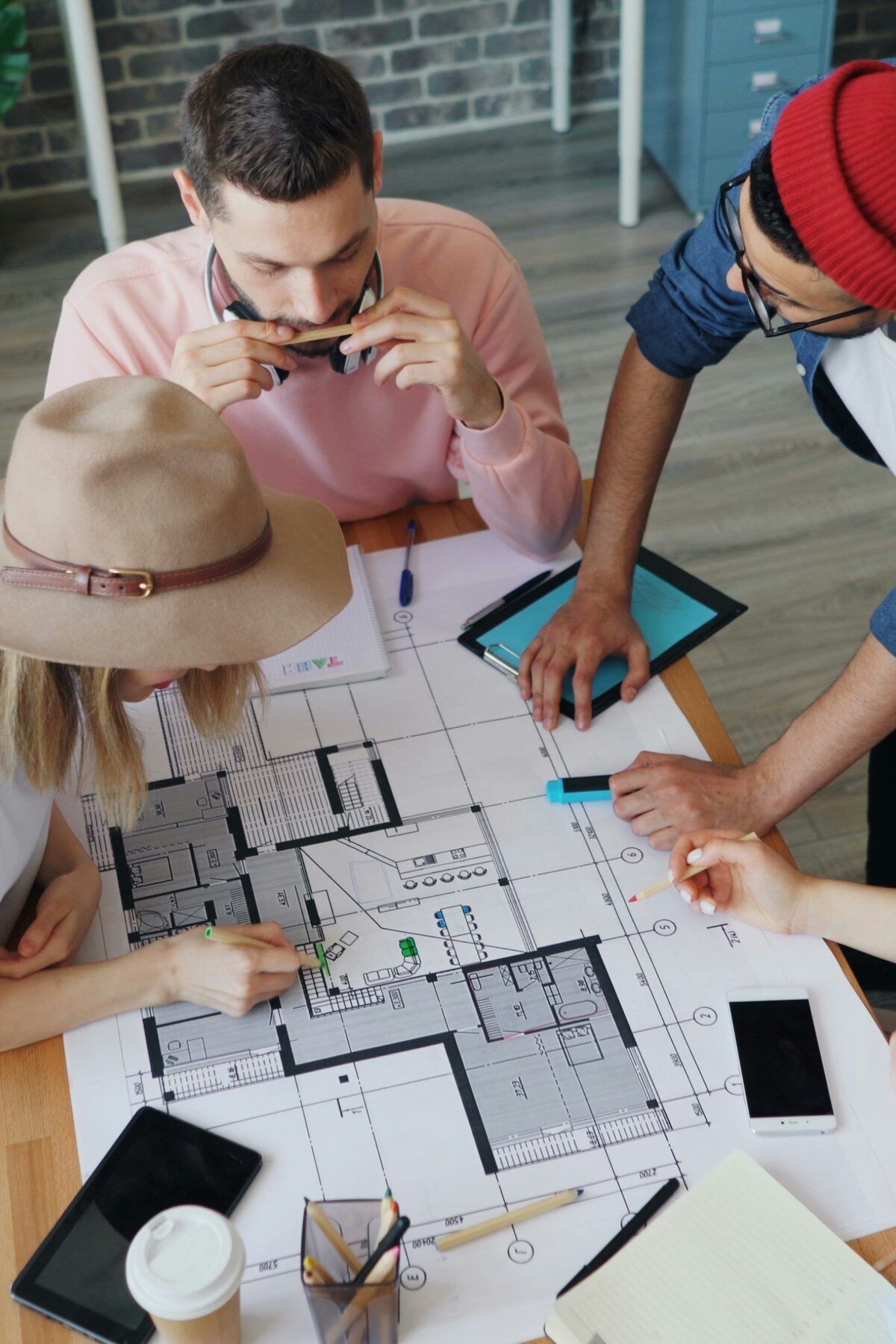 Colleagues around a table marking up a printed floor plan