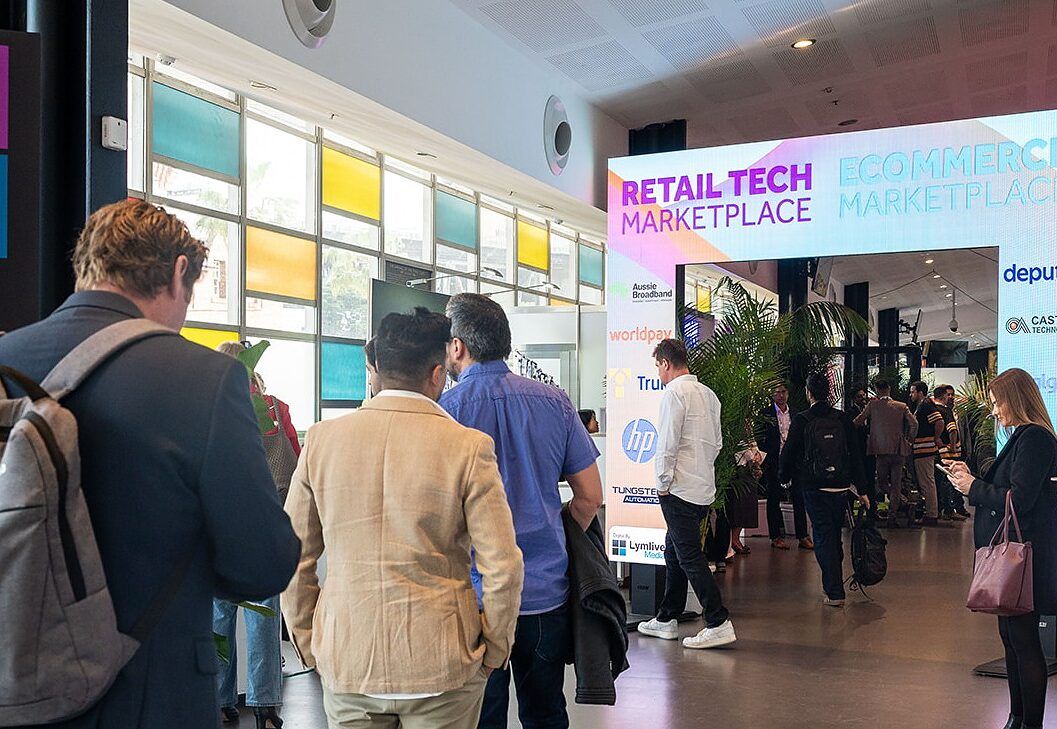 Attendees walking through the entrance arch onto the busy event floor