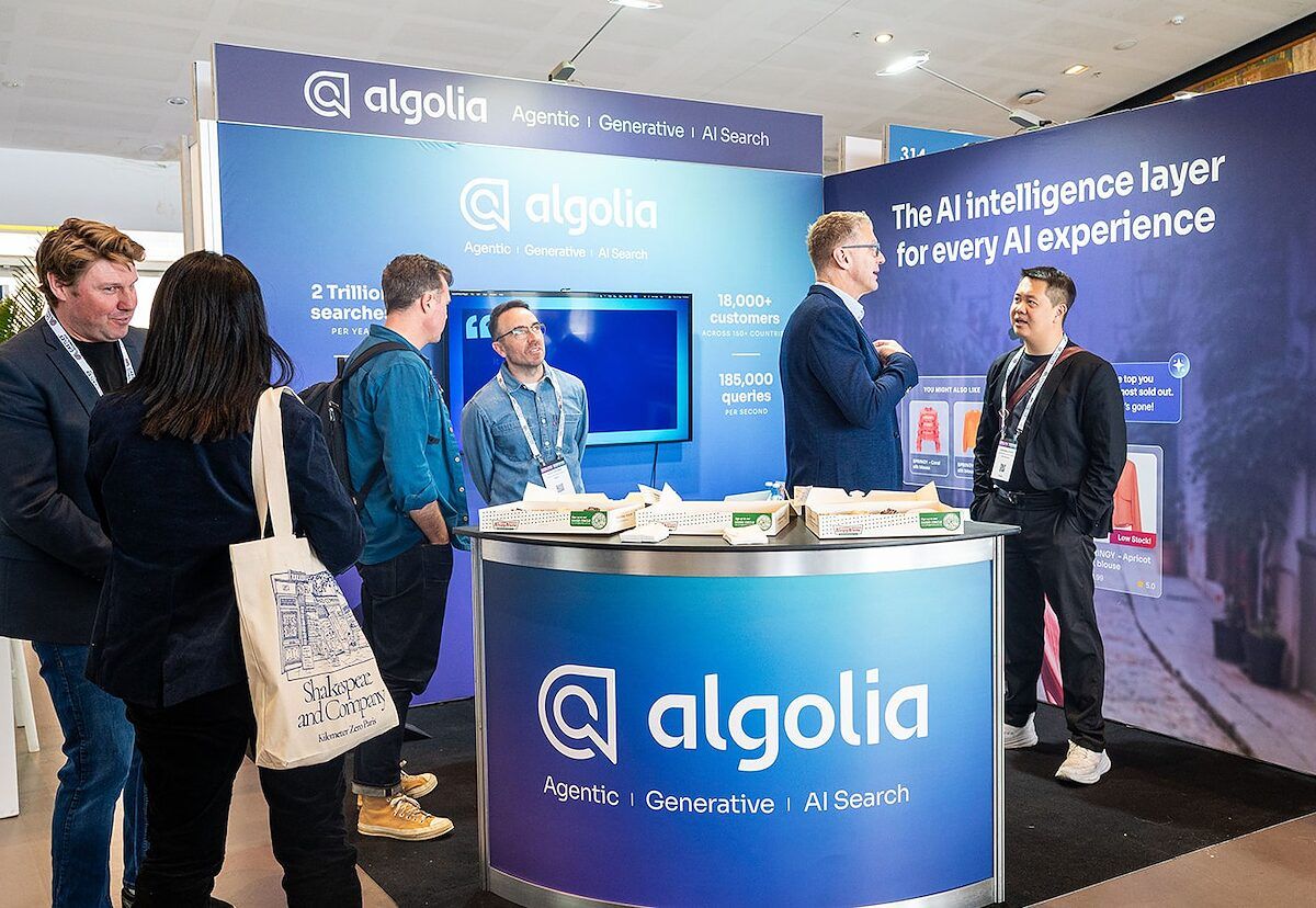 Visitors and exhibitors talking around the counter of a search software stand
