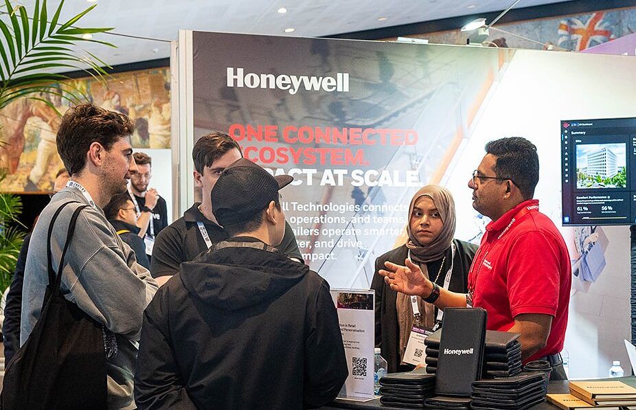 Visitors and exhibitors talking in front of a large product display at a stand