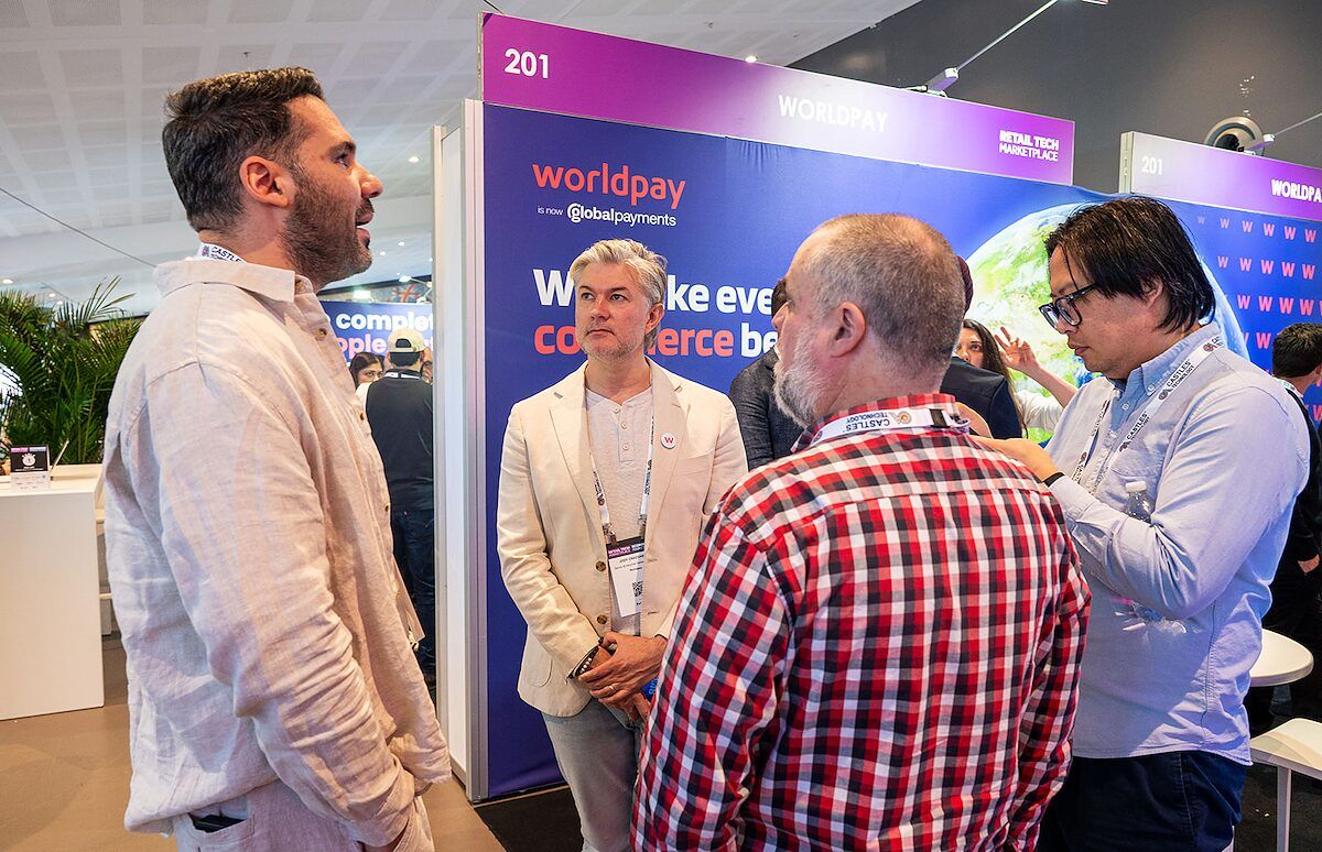 Visitors and exhibitors in conversation at a payments stand