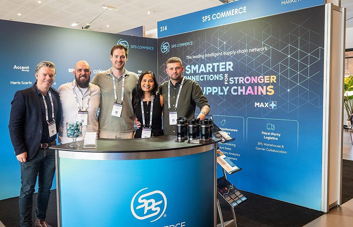 An exhibitor team standing together behind the counter of their stand