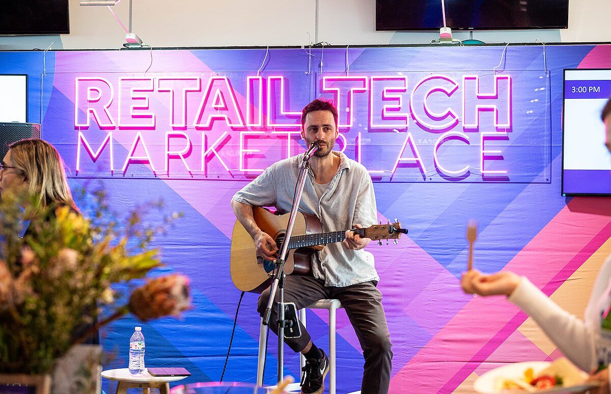 A musician playing an acoustic guitar on stage at the event