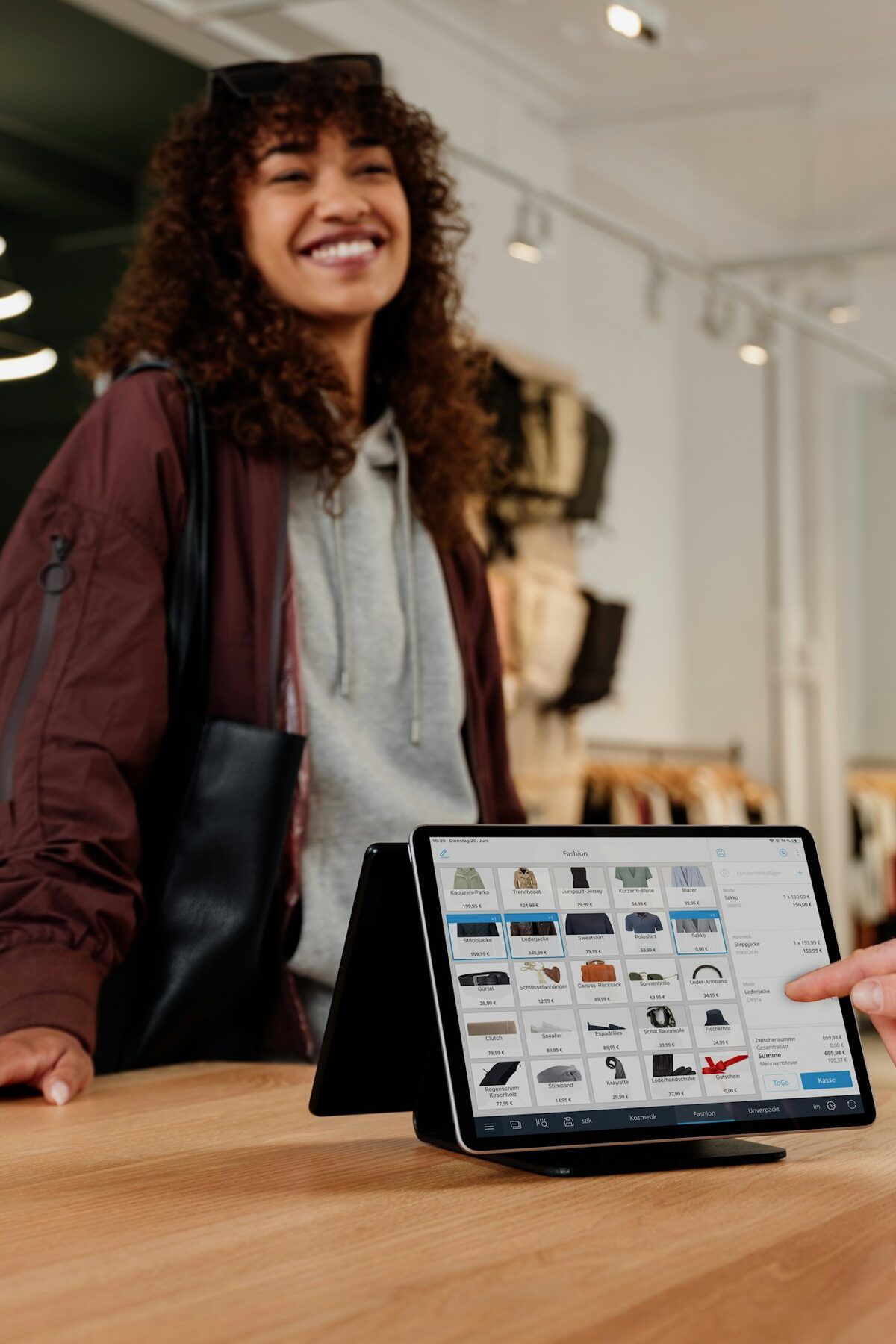 A shopper at a store counter while staff use a tablet point-of-sale system