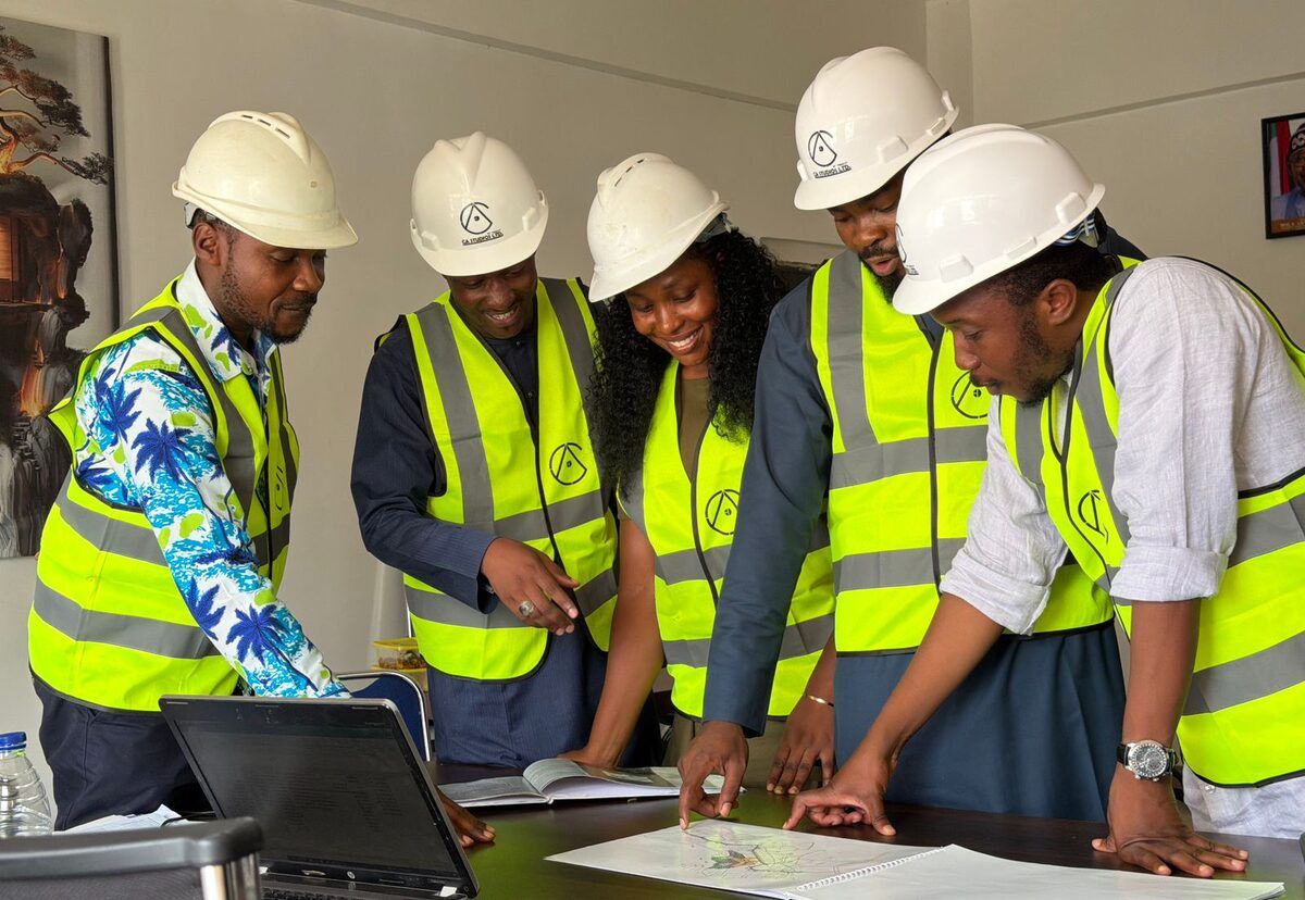 A team in safety vests reviewing plans around a laptop